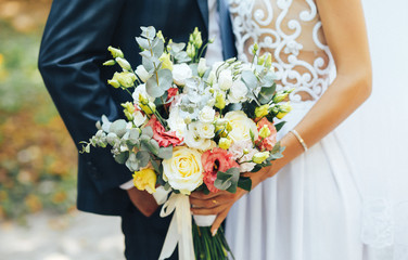 stylish and beautiful wedding bouquet in the hands of the bride and groom