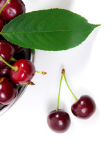 Steel colander with red sweet cherry isolated on a white background..