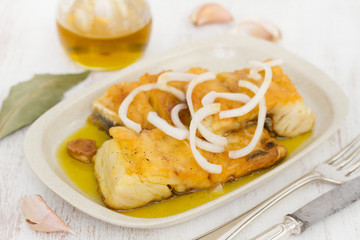 fried cod fish with onion and olive oil on dish