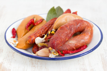 smoked sausages on white dish on wooden background