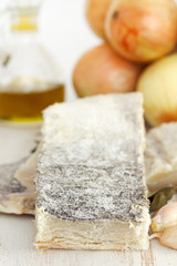 salted dry codfish with oil, garlic and onion on wooden background