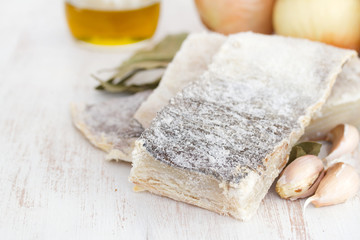 salted dry codfish with oil, garlic and onion on wooden background