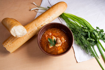 Borsch - traditional Ukrainian and Russian red beetroot soup with red beets in clay bowl on wooden background..