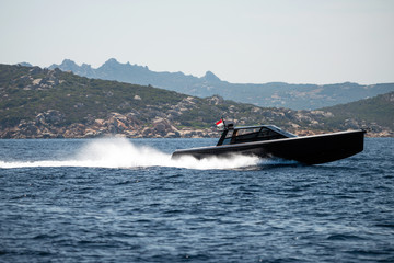 Fototapeta premium Small motor boat on sea, Sardinia island in background