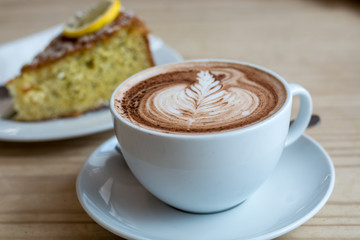 Hot chocolate with cream in the shape of a leaf and lemon cake