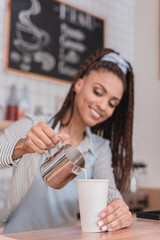 barista pouring milk into coffee