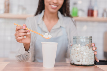 barista putting marshmallows into cup