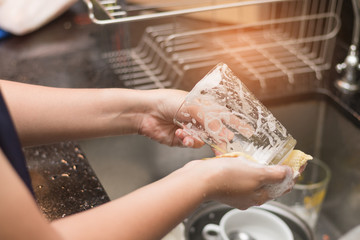A woman washing glass by dish soap