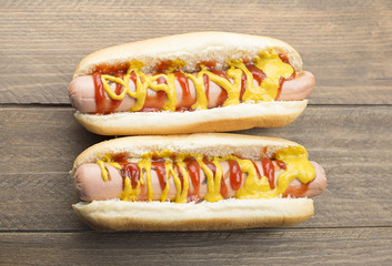 Two hotdogs with ketchup and mustard on wooden table. Fastfood.