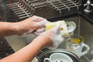 A woman washing stainless spoon by dish soap