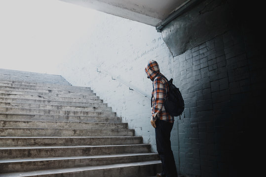 Hipster in a checkered shirt rises the stairs from the underpass