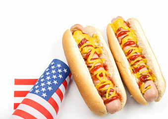 Two hotdogs with ketchup and mustard next to American flag on white background. Isolated. Fastfood.