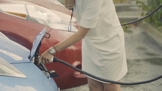 Woman charges electric car during rain