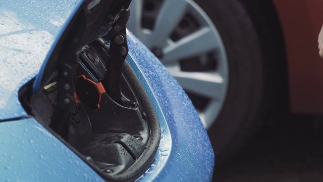 Woman opens the charge connector of electric car with remote control