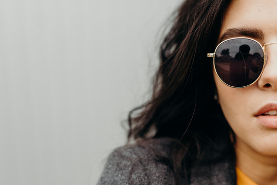 Portrait of stylish modern young curly woman in coat sunglasses