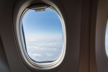 Single window of an airplane with clouds