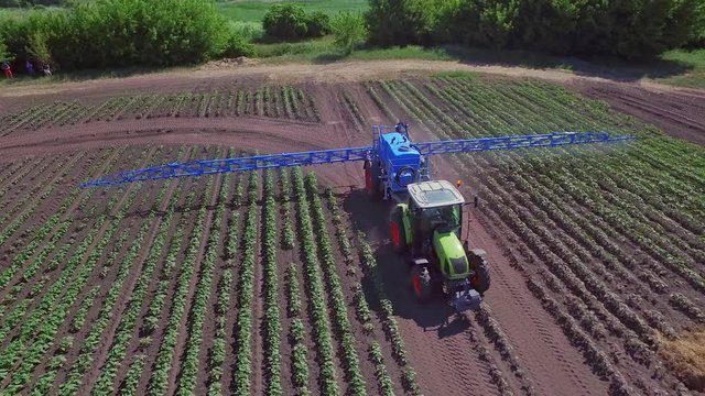 Agriculture watering. A griculture fertilizer irrigation farming field. Sky view fertilizer spreader working on agricultural field. Process watering field in farming industry