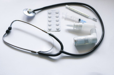 Stethoscope, syringe, inhaler, spray and pills isolated on white background