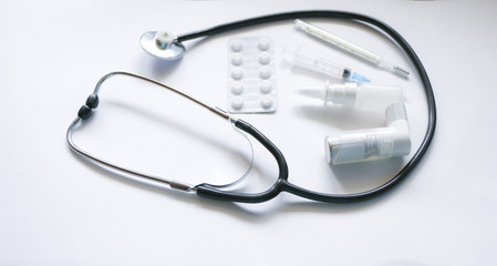 Stethoscope, syringe, inhaler, spray and pills isolated on white background