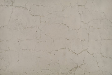 White-gray surface of a wall with cracked paint, plaster, close-up 