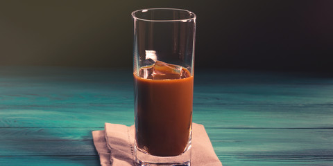 Glass of iced coffee on dark green and black background
