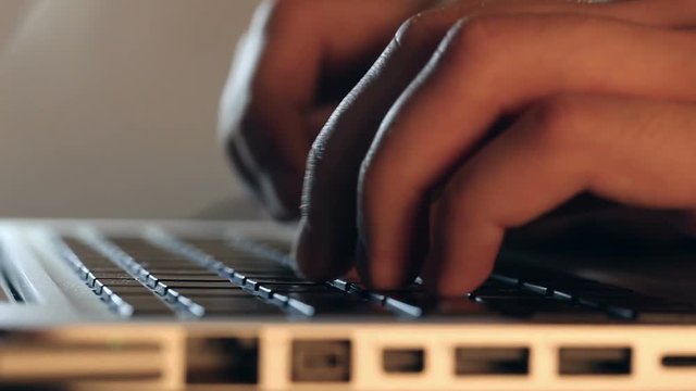 Closeup refocusing shot of writer's hands typing on a laptop keyboard.