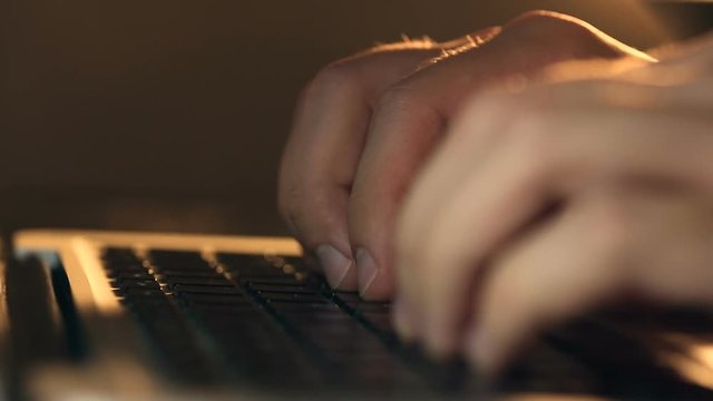 Closeup refocusing shot of writer's hands typing on a laptop keyboard.
