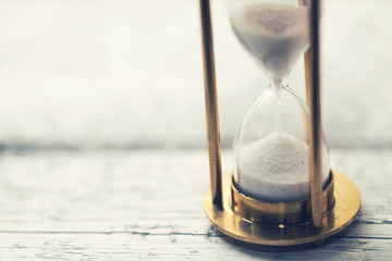 time is ticking - hourglass on the table with copy space - obrazy, fototapety, plakaty