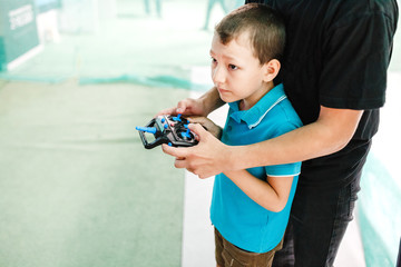 Adorable boy playing with wireless remote control with quadrocopter toy with his dad