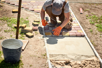 Laying Paving Slabs by mosaic close-up. Road Paving, construction. Repairing sidewalk. Worker laying stone paving slab. Laying colored tiles in city park (garden). Hand fixed tessellated sidewalk tile