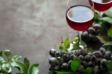 Still life with wineglasses, bottles, grapes and leaves on brown wooden desk