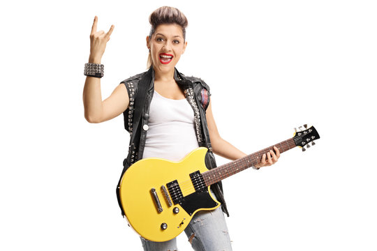 Joyful punk girl with an electric guitar making rock hand gesture