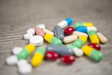 Medicine pills, tablets and capsules on wooden background.