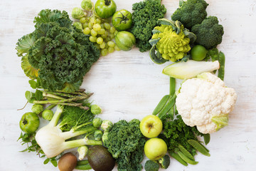 Above view of green vegetables and fruits arranged in a circle frame, copy space for text in the middle, selective focus