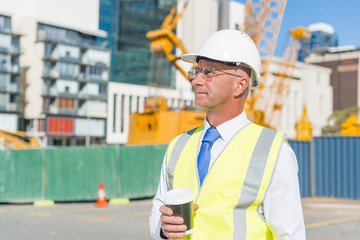 Engineer builder on construction site at sunny day with coffee in hand