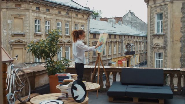 The artist paints a painting on the balcony of the workshop. The old Town. Contemporary art, abstract. Slow motion. Shot on RED Epic Camera.