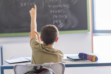 Student with hands up in classroom during a lesson