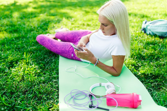 Photo of sporty woman with phone on rug
