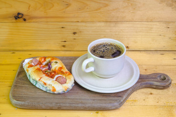 Obraz premium Cup of coffee and mini pizza on wooden cutting board