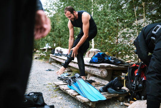 Male diver in wetsuit checking equipments before immerse