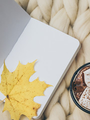 Cozy composition, hot chocolate with marshmallows, merino wool blanket, warm and comfortable atmosphere. Knit background. Flat lay.  Top view. Copy space. Autumn concept.