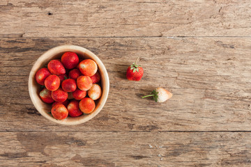 Strawberries in a wooden bowl on wood table