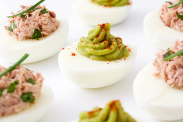 Variety of stuffed eggs with avocado and tuna  isolated on white background
