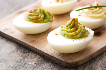Stuffed eggs with guacamole on wooden table