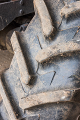 A big used dirty farm tractor tread, with big strong gripping treads. Industrial agricultural tyres.