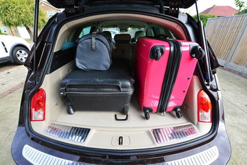 Suit cases packed for a holiday into an estate car.