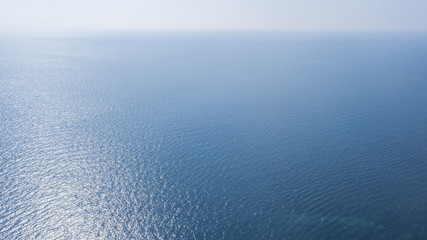 Fototapeta na wymiar Vista aerea della superficie blu delle acque dell' oceano atlantico. Il sole, sopra l'orizzonte, riflette i suoi raggi solari sul mare.