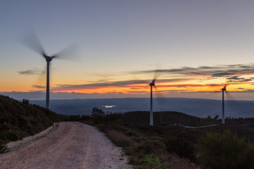 Magic sunset on the road with wind generators for electricity.