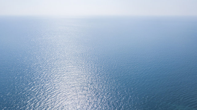 Vista aerea della superficie blu delle acque dell' oceano atlantico. Il sole, sopra l'orizzonte, riflette i suoi raggi solari sul mare.