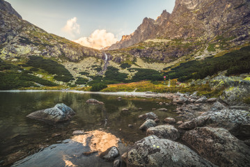 Mountain Lake with Waterfall and Rocks in Foreground at Sunset. Velicka Valley, High Tatra, Slovakia.